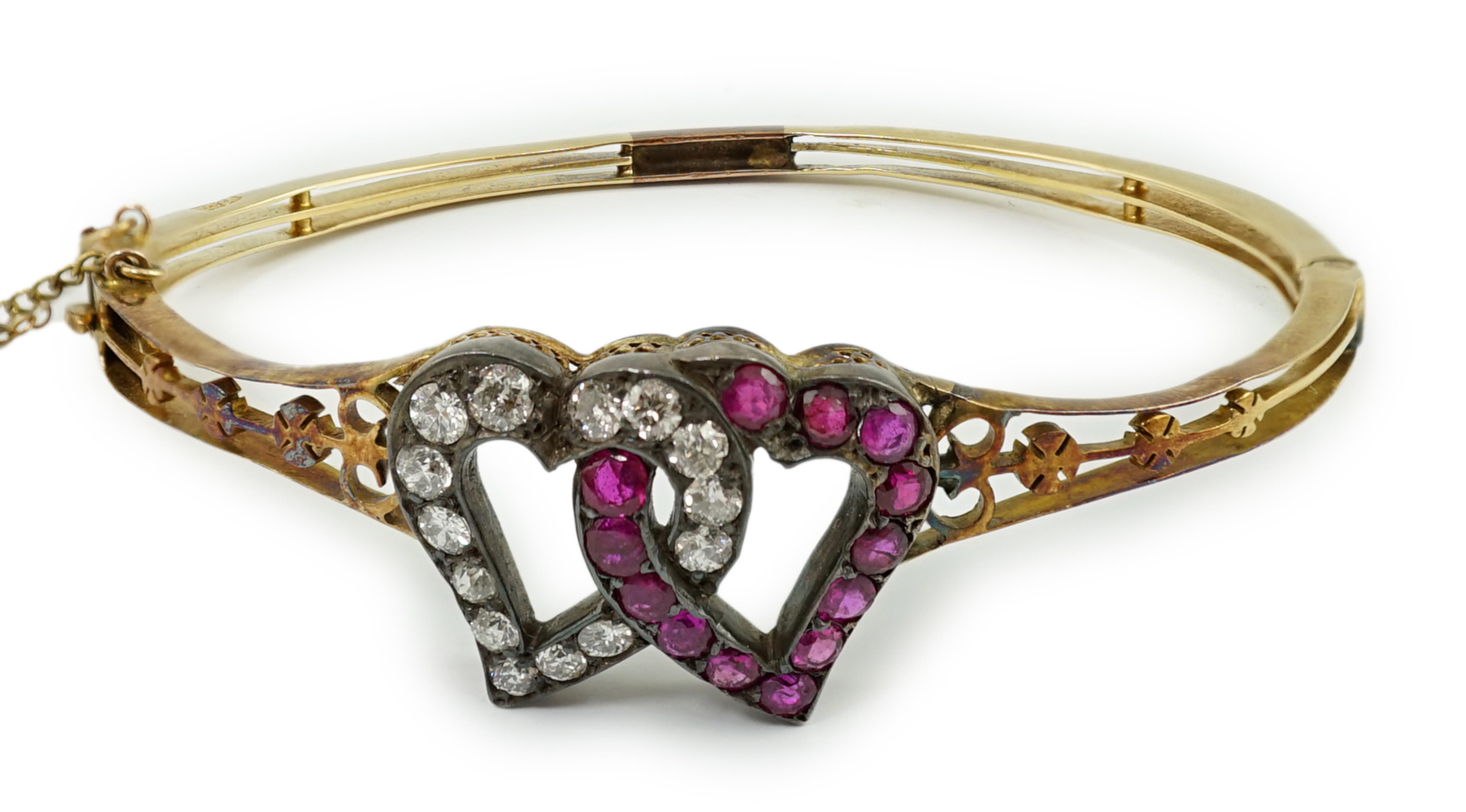 A Victorian pierced 18ct gold, ruby and diamond set twin hearts hinged bangle